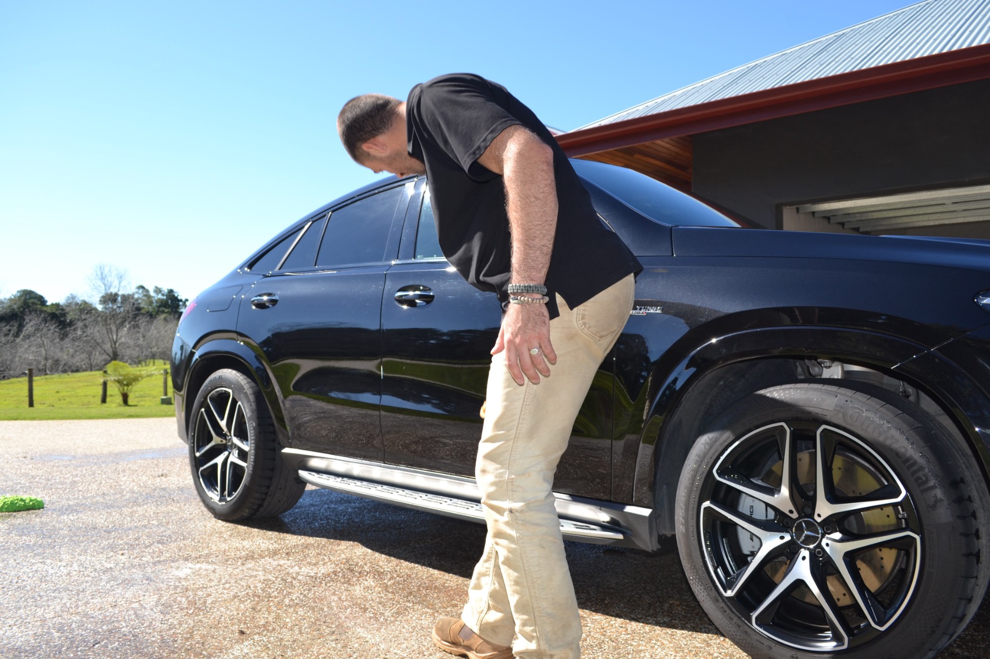 Antoine checking the wheels of a black Mercedes-AMG